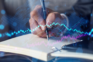 Businessman in suit taking notes. Multiexposure with forex graph hologram. Man writing down important information in his business diary. Financial trading concept.