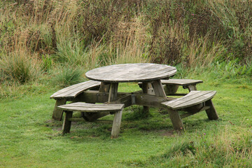 A Round Wooden Outdoor Picnic Table with Seats.