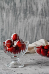 fresh red strawberries poured with white cream on a glass in a dessert cup