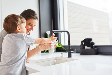 Obraz na płótnie Canvas Mutter hilft Kind beim Händewaschen mit Seife