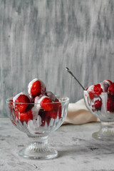 fresh red strawberries poured with white cream on a glass in a dessert cup