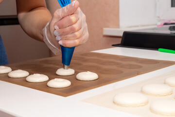 On parchment spread the dough for macaroons from the pastry bag before baking. Cooking process.