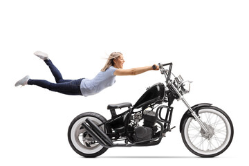 Fototapeta na wymiar Young woman flying and holding on to a black chopper motorbike