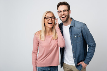 Smiling couple in eyeglasses standing isolated on grey