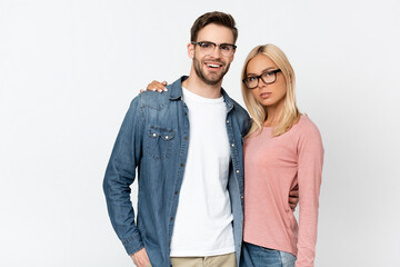 Blonde woman hugging smiling boyfriend in eyeglasses isolated on grey