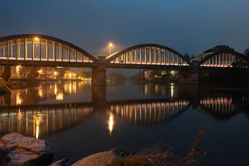 Fototapeta na wymiar Brivio bridge at night with reflection in the Adda river
