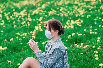 Young woman with face mask outdoors in blossom garden. Corona virus concept.