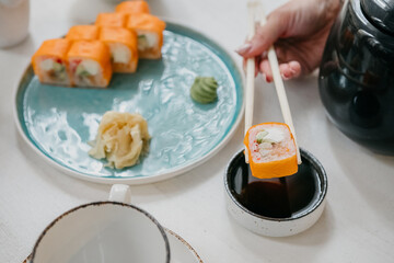 Philadelphia rolls on a white plate with soy sauce and ginger