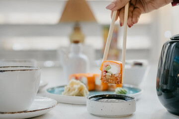 Philadelphia rolls on a white plate with soy sauce and ginger