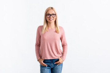 Obraz premium Front view of happy blonde woman with hands in pockets, wearing eyeglasses and looking at camera isolated on white