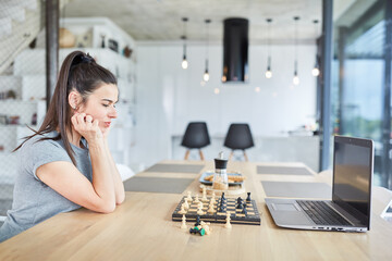 Frau zu Hause beim Schach spielen am Laptop Computer