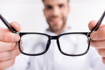 Eyeglasses with black frame with blurred doctor on background