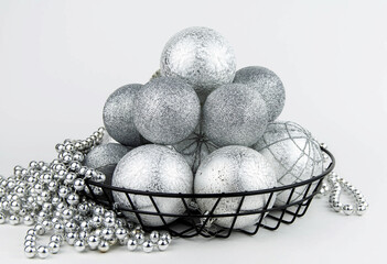 Christmas composition. Christmas balls and silver beads in an iron basket on a white background.