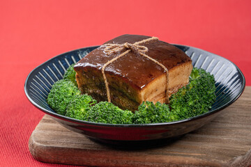 Dong Po Pork meat in a blue plate with broccoli with red background.