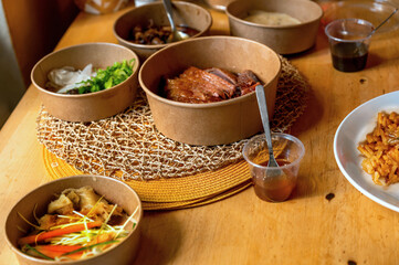 Table with many paper bowl with asian meal from restaurant delivery.