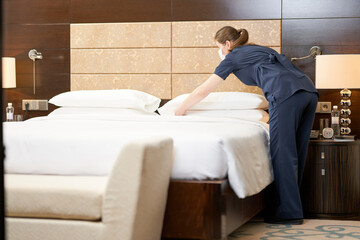 Professional chambermaid cleaning a luxury hotel room