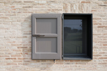 window with grey open shutter on a brick wall, space for text and no person