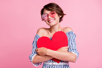 Photo portrait of cute girl hugging big red heart postcard wearing rose-tinted glasses isolated on...