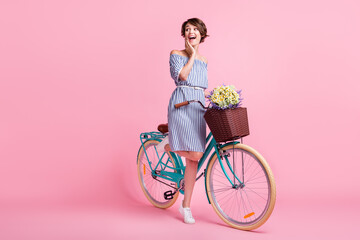 Photo portrait of excited girl touching face with hand standing on one leg holding bicycle with...