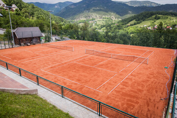 Slag tennis court with beautiful mountain view on summer day.