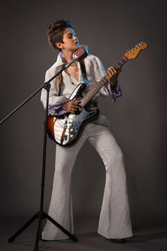 A teenage guy in the image of Elvis Presley with a guitar and a concert suit