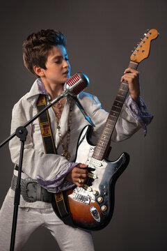 A teenage guy in the image of Elvis Presley with a guitar and a concert suit