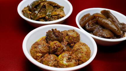 Group photograph of indian pickles or achar like amla pickle, mango pickle and lemon pickle, sarved in white ceramic bowl, selective angle