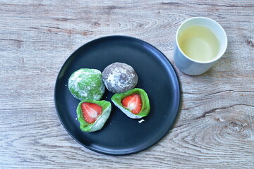 Daifuku stuffed fresh strawberry Japanese sweet made from flour and bean on plate eat couple hot tea cup