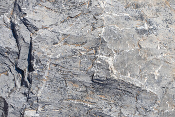Rough texture of mountain wild stone. Marble. Granite. Stone abstraction. Mountain stone. The rough surface of an ancient mountain. Grunge texture. Laminated surface. Abstract grunge background.