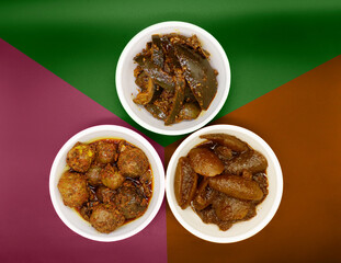 Group photograph of indian pickles like mango pickle , lemon pickle and amla pickle, sarved in white ceramic bowl, selective focus