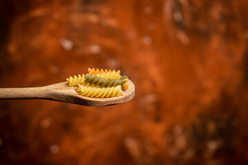 Various mix of dry pasta on wooden spoon