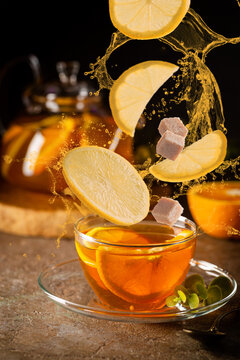 Glass teapot with hot citrus tea from oranges, lemons and limes, healthy drink on dark background. Picture with levitation