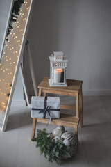Details of Christmas interior. White lantern with candle and present standing on a wooden table.