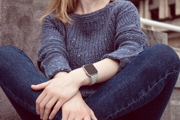 Fototapeta premium Young beautiful woman in a cozy blue sweater spends time outdoors. Lifestyle portrait of female
