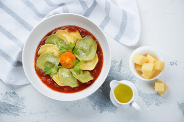 Bowl of italian ravioli with tomato sauce and grated parmesan cheese, flatlay on a white concrete background, studio shot
