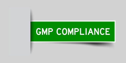 Inserted green color sticker label with word GMP (Abbreviation good manufacturing practice) complianceon gray background