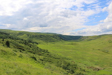 Fototapeta na wymiar A tranquil and beautiful landscape image of a lush, empty, green valley with clouds and blue sky above it.