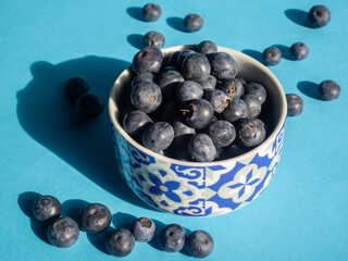 blueberries in a porcelain cup with horizontal blue background