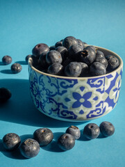 blueberries in a porcelain cup with vertical blue background