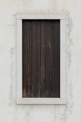 Fototapeta premium old window with wooden shutters, white wall with cracked and peeled, vertical format with space for text