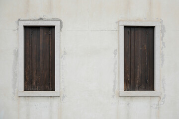 Fototapeta na wymiar two old window with wooden shutters on a bright wall, no person an space for text, horizontal 