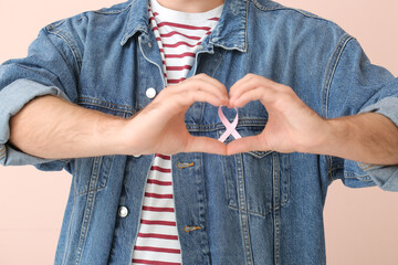 Man with pink ribbon on color background, closeup. Breast cancer awareness concept