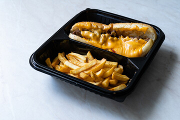 Take Away Philly Cheese Steak Sandwich with Melted Cheddar Cheese and Potatoes in Plastic Container Plate Package.