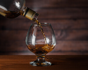 Cognac is poured from a bottle into a glass, close-up