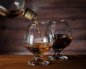Cognac is poured from a bottle into a glass, close-up