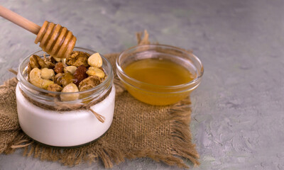 Greek yogurt with honey and different nuts on a gray background.
Copy space.