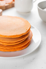 Tasty pumpkin pancakes on table