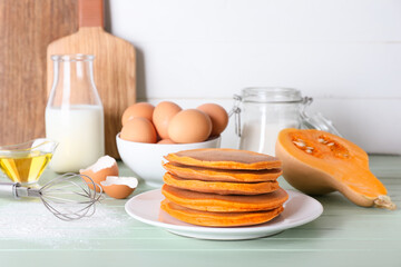Tasty pumpkin pancakes with ingredients on table