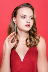 Fototapeta premium young woman in earrings looking away on red