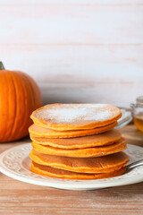 Tasty pumpkin pancakes on table